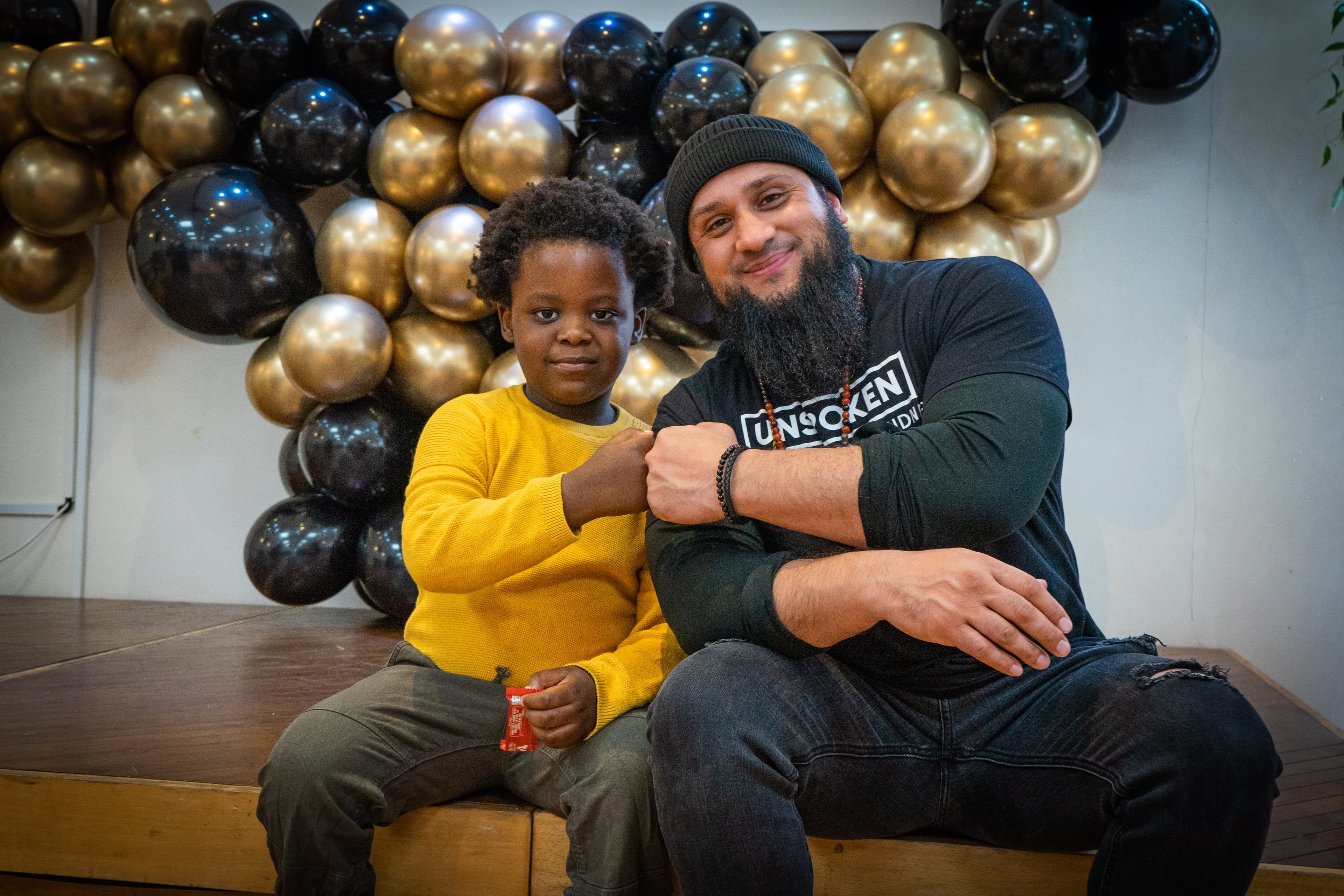 Atiq with a child at an Unspoken event - background